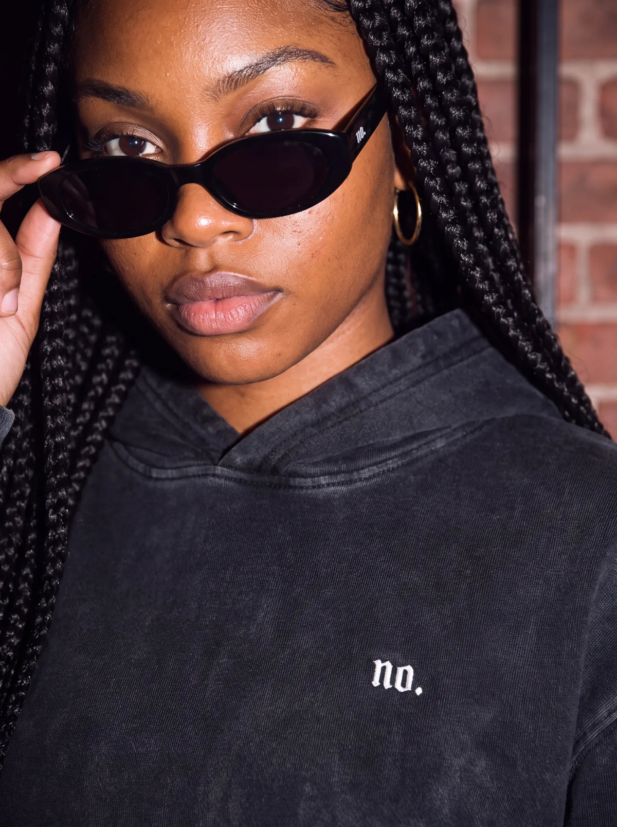 Woman in sunglasses wearing the 'no.' hoodie, small 'no.' chest print