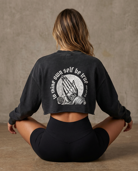 Woman seated cross-legged showing the "to thine own self be true" back print on the cropped sweatshirt